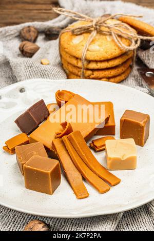 Brunost norvegese con biscotti e noci. Cibo sano e mangiare, ingrediente biologico per la prima colazione. Tradizionale formaggio marrone scandinavo, retro in legno Foto Stock