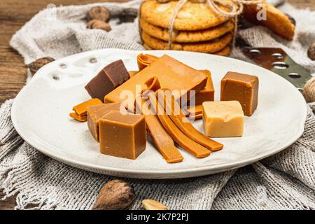 Brunost norvegese con biscotti e noci. Cibo sano e mangiare, ingrediente biologico per la prima colazione. Tradizionale formaggio marrone scandinavo, retro in legno Foto Stock