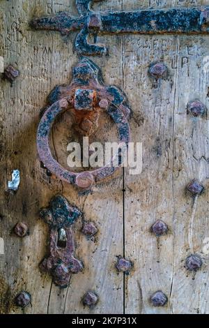 Porta medievale con borchie, legno intemperiato, maniglia per porta arrugginita, serratura e cerniera Foto Stock