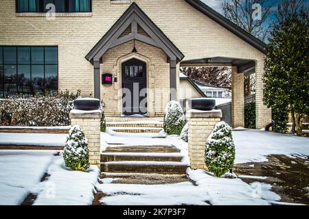 Casa in mattoni chiari nella neve - Porte Cochere e marciapiede con gradini che sono stati salati - paesaggistica e lettera rosa fissato alla cassetta postale Foto Stock