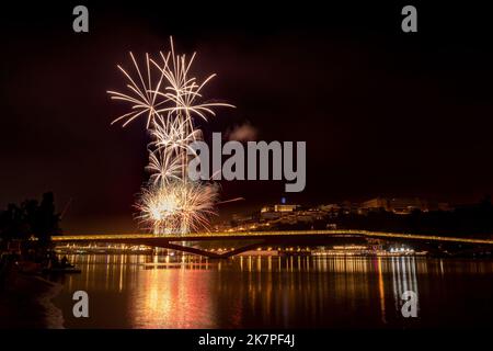 Fuochi d'artificio ai festeggiamenti nella città di Coimbra 2022, in Portogallo, con il fiume Mondego e il ponte pedonale Pedro e Inês in primo piano Foto Stock