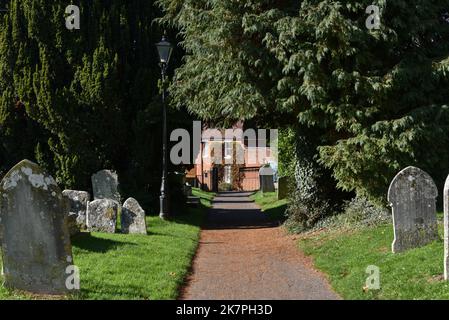 Il sentiero di campagna coperto da alberi conduce da un cimitero di una chiesa fino a un villaggio rurale dell'Hampshire, Inghilterra. Foto Stock