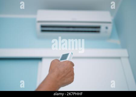 Mano con comando a distanza diretto sul climatizzatore Foto Stock