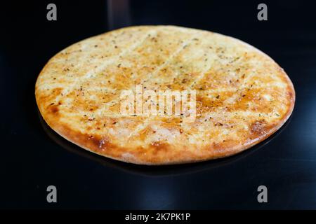 Pizza a fette su sfondo di pietra nera, vista dall'alto. Focaccia appena sfornata con formaggio Foto Stock