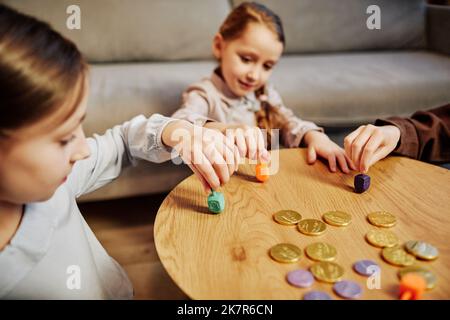 Ritratto di tre bambini che giocano a un tradizionale gioco di dreidel in un'illuminazione calda e accogliente, spazio copia Foto Stock