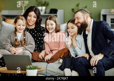 Ritratto della famiglia ebraica moderna utilizzando il computer portatile e le chiamate tramite chat video in un ambiente accogliente casa Foto Stock
