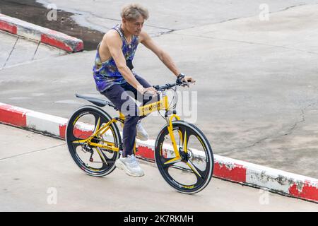 SAMUT PRAKAN, THAILANDIA, 23 2022 SETTEMBRE, Un uomo cavalca una mountain bike pieghevole su una strada cittadina Foto Stock