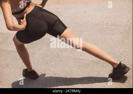 Ragazza sportiva che fa affondo le gambe durante l'allenamento all'aperto Foto Stock