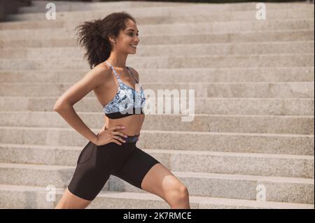 Ragazza sportiva che fa affondo le gambe durante l'allenamento all'aperto Foto Stock