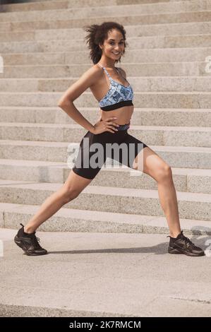 Ragazza sportiva che fa affondo le gambe durante l'allenamento all'aperto Foto Stock