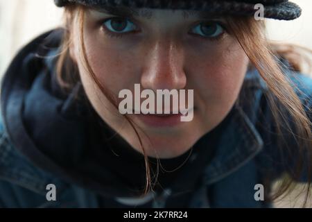 Ritratto sfocato di giovane donna caucasica sorridente all'aperto. Donna elegante e luminosa in cappello. Millennial e hippster. Capelli di vento. Fuori fuoco Foto Stock