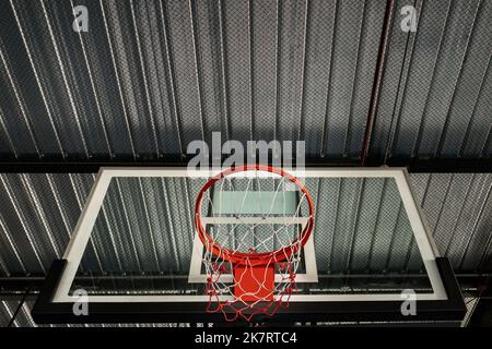 Bangkok, Thailandia - 10 ottobre 2020 : Vista dal fondo del backboard in fibra di Pallacanestro, anello di metallo rosso Hoop e rete bianca contro la lamiera del soffitto in th Foto Stock