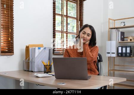 Donna asiatica d'affari che ha dolore al collo mentre lavora su un computer portatile. concetto di sindrome dell'ufficio. Foto Stock
