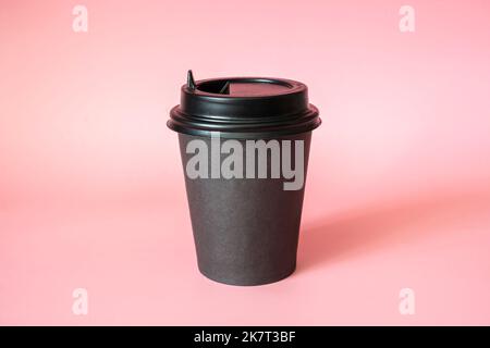 Tazza di caffè in carta nera su sfondo rosa. Spazio vuoto per testo e design. Modulo per il nome del caffè, dell'azienda o del bar Foto Stock