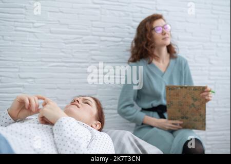 Una donna di mezza età si trova su un divano e parla con uno psicologo. Foto Stock