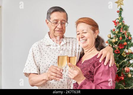 Felice coppia ispanica anziana brinda durante Natale o Capodanno, festeggiando le vacanze a casa, avendo un buon tempo insieme. Foto Stock