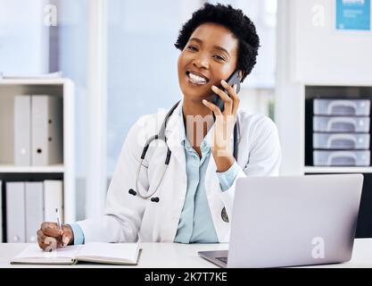 Im felice di sentire youre fare bene. una giovane e attraente dottoressa che prende appunti mentre fa una telefonata nel suo ufficio. Foto Stock