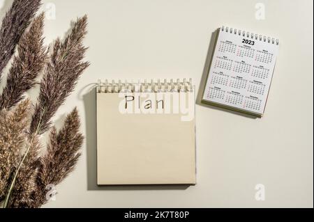 2023 volta per il nuovo inizio. Parola e calendario del piano 2023 su sfondo bianco della tabella. I piani di Capodanno per il 2023, spazio per il testo sul blocco note, calendario su d Foto Stock