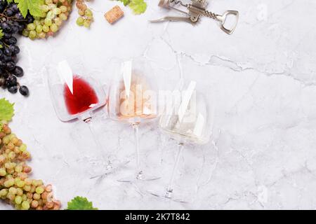 Bicchieri da vino e uva bianchi, rosati e rossi. Giacitura piatta Foto Stock