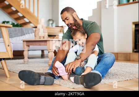 Lascia vestirsi e poi possiamo giocare. un padre che aiuta sua figlia ha messo i calzini sui suoi piedi a casa. Foto Stock