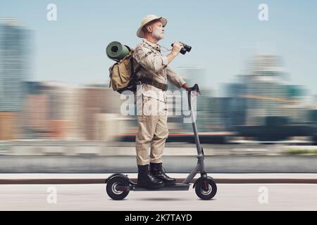 Divertente esploratore urbano senior in sella a uno scooter elettrico veloce nella strada della città Foto Stock