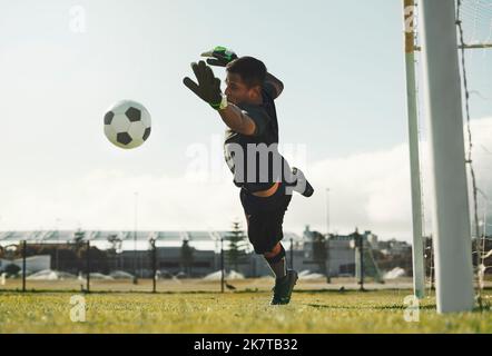 Calcio, portiere e salto, salvando palla da gol in campo sportivo all'aperto. Calcio, portiere e gioco da competizione con fitness, portiere e Foto Stock