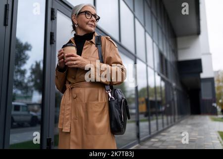 una donna anziana di successo si trova all'ingresso del business center Foto Stock