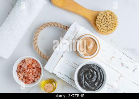 Vista dall'alto dei trattamenti spa a casa. Maschera di argilla in un boel, scrub viso, sale himalayan rosa e pennello viso con setole naturali. Procedure di cura della pelle per Foto Stock