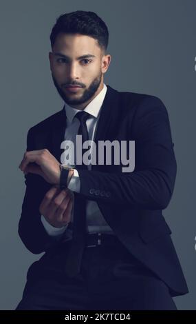 Un vero uomo d'affari deve vestire la parte. Foto studio di un giovane che si posa su uno sfondo grigio. Foto Stock