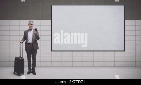 Uomo d'affari in viaggio in attesa alla stazione della metropolitana e cartello commerciale vuoto, viaggio e concetto di trasporto Foto Stock