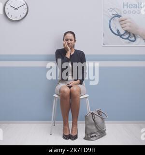 Paziente seduto in sala d'attesa presso la clinica dentale: Sta avendo un mal di denti cattivo Foto Stock