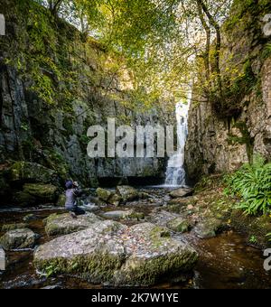 Un fotografo cattura la grandezza della cascata Catrigg Force, sopra il villaggio di Stainforth, Yorkshire Dales, Regno Unito. Foto Stock