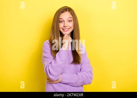 Foto di Dreamy minded ragazza adolescente intelligente indossare maglia viola maglione toccare mento Dreamy sorridente look che si isolato di colore giallo Foto Stock