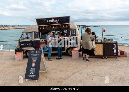 Sitges, Barcellona, Spagna - 08 ottobre 2022: : Gente che compra il cibo ad un camion di fast food sulla passeggiata con il mare sullo sfondo Foto Stock