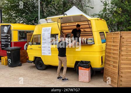 Sitges, Barcellona, Spagna - 08 ottobre 2022: Furgone retrò giallo pronto a vendere fast food per la strada con un cliente che ordina patatine e pesce Foto Stock