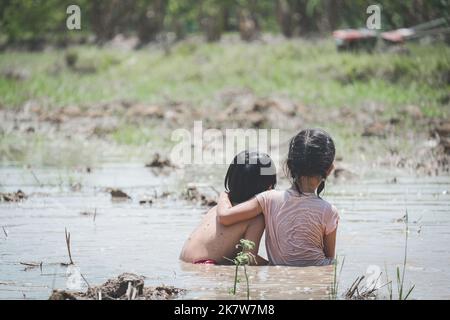 Due bambini si rilassano felicemente nel fango nei campi della campagna Foto Stock