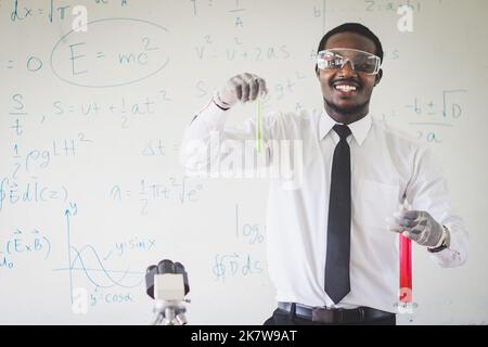 Insegnante di scienze africane che conduce esperimenti miscelando liquidi in matraccio, assistente di laboratorio in occhiali che mostrano la reazione chimica in lezione, chimica Foto Stock