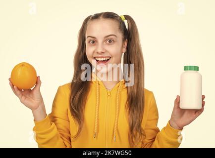 ragazza scegliere tra frutta d'arancia e pillola di vitamina in vaso bottiglia isolato su bianco, multivitaminici. Foto Stock