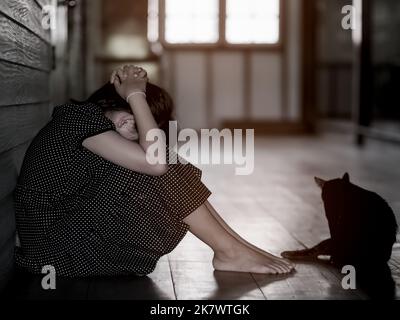 Triste solitario bambina piangendo mentre si siede sul pavimento in camera oscura con un atteggiamento di tristezza.concetto di depressione o violenza domestica bambino Foto Stock