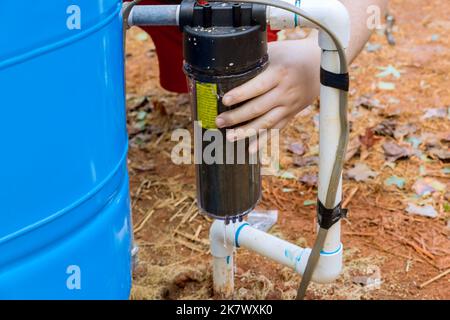 Un operatore professionale esegue la manutenzione delle apparecchiature, inclusa la sostituzione dei filtri sostituibili per l'acqua all'esterno vicino alla casa Foto Stock