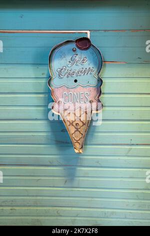 Grande segno al neon di gelato verde e rosa su sfondo verde a strisce. Foto Stock