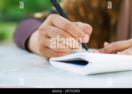 Primo piano di donne mano scrivere su blocco note. Foto Stock