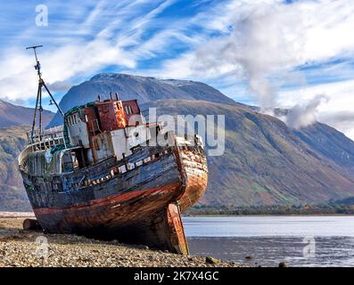 Corpach Fort William Scotland ben Nevis e l'orlo della vecchia barca di Caol abbandonati sulla spiaggia di ciottoli Foto Stock