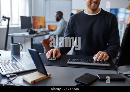Immagine ritagliata di uno sviluppatore di software maschio presso una workstation per computer, spazio di copia Foto Stock
