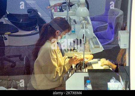 Ragazza cinese che fa le unghie dei clienti nel salone delle unghie Foto Stock