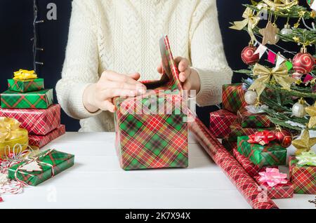 Passo per passo Foto istruzioni per la confezione di un regalo di Natale, Passo 5 - piegatura degli angoli laterali della carta da imballaggio. Foto Stock