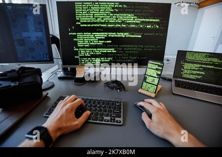 POV ripresa del programmatore di computer che lavora con linee di codice verdi su schermi di più dispositivi, spazio di copia Foto Stock