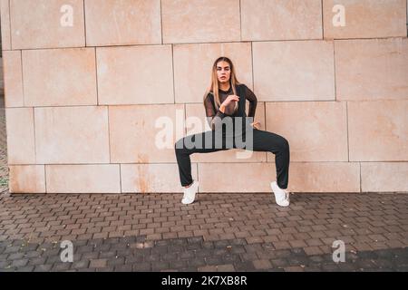 Giovane donna sorridente in abiti casual posizionamento per danza contemporanea sulla strada cittadina Foto Stock