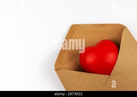 Primo piano della forma del cuore in una busta marrone su sfondo bianco Foto Stock