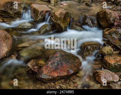 Una roccia di colore rossastro ha acqua che scorre intorno a essa nel Glen Creek di Parfrey, nella riserva naturale di Parfrey Glen state nella contea di Sauk, WISCONSIN Foto Stock